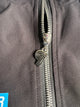 Close-up of Primoir jacket zipper featuring custom silver 'P' logo pull on black fabric