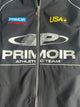Close-up of Primoir USA+ jacket showing chest branding with siler zipper, Primoir logo, and USA+ patch